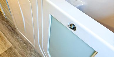 Close-up of a white bathtub with a frosted glass panel and chrome knob.