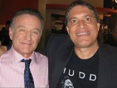 Two men posing and smiling indoors, one in a suit and the other in a casual jacket.