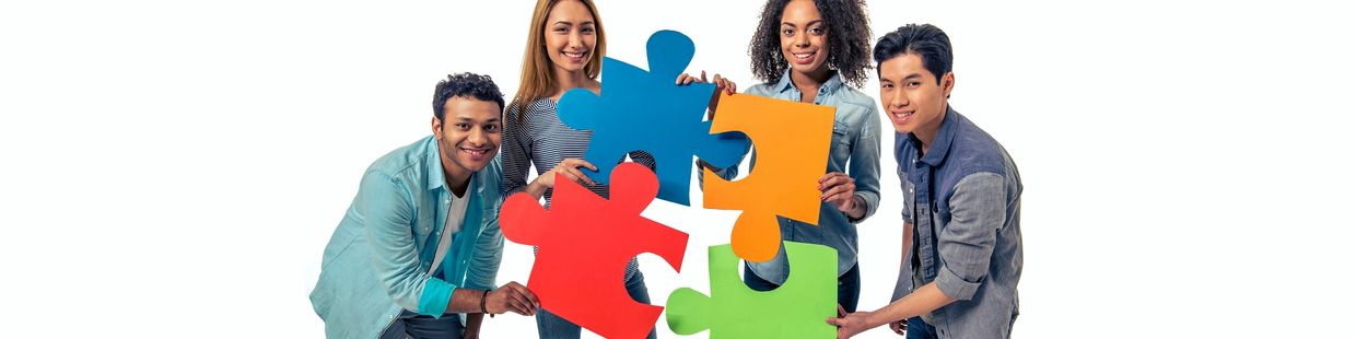 Diverse team holding large puzzle pieces.