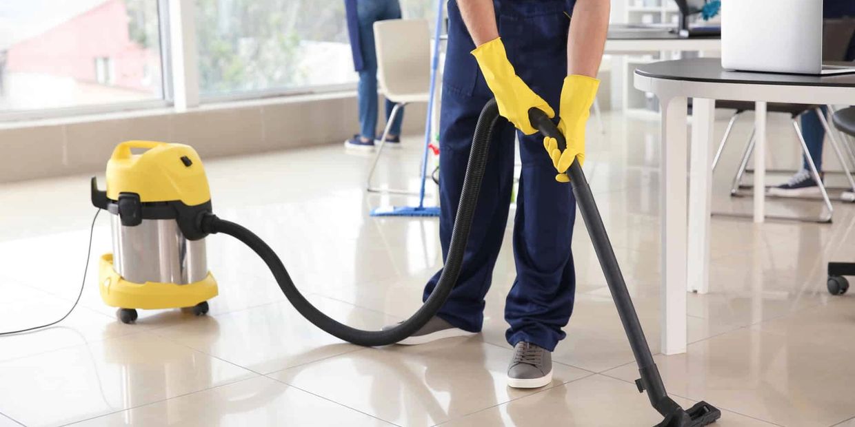 Person vacuuming floor in a clean office space.