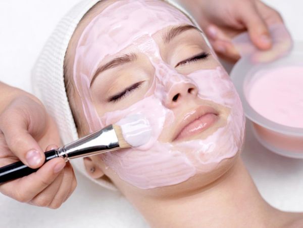 Woman receiving a pink facial mask treatment.