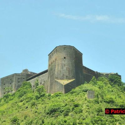 Historic fortress atop a lush green hill under a clear blue sky.