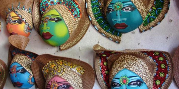 Colorful decorative masks with painted faces and woven hats.