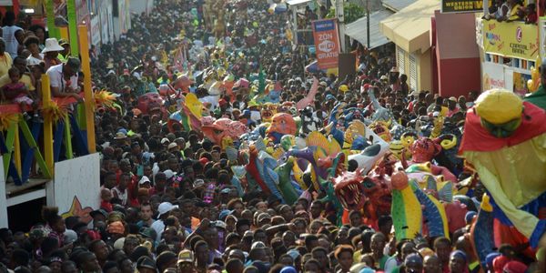 Colorful festival parade with large crowd and vibrant masks.