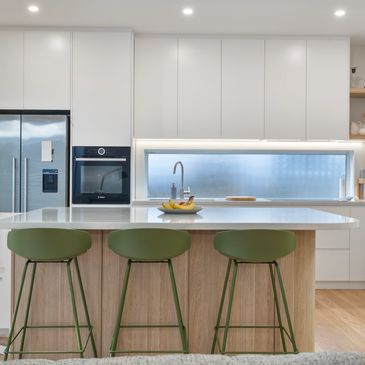 Renovated kitchen with white cabinetry, oak look kitchen island. Green chairs