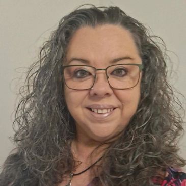 Smiling woman with glasses and curly hair.