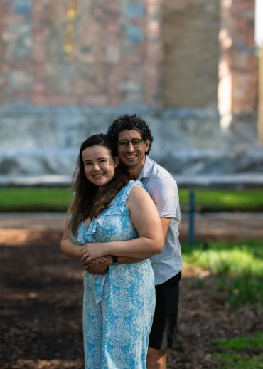 Couple smiling and embracing outdoors in a park setting.