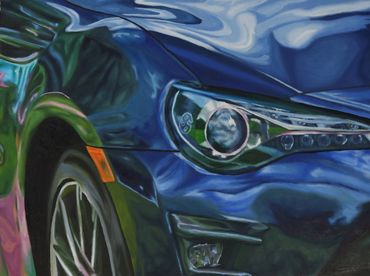 Close-up of a shiny blue car's front headlight and wheel.