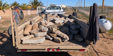 Truck bed filled with large concrete debris and rocks.