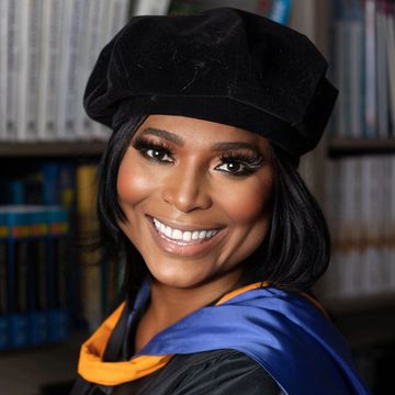 Smiling graduate in cap and gown.