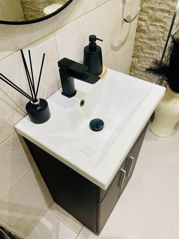 Modern bathroom basin with black faucet and accessories
