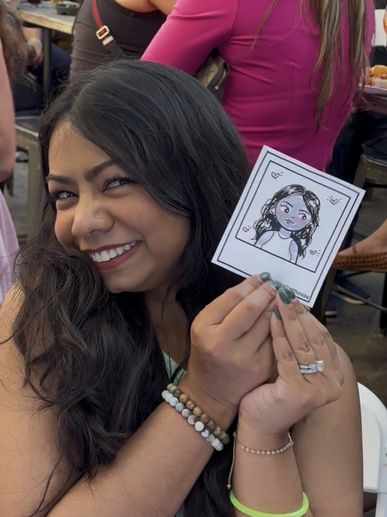 Woman smiling and holding a cute cartoon portrait of herself.