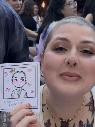 Person holding a cartoon portrait of themselves with hearts and a love message.