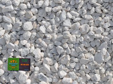 White, washed, limestone rock with Coastal Landscape Supplies business card in the corner.