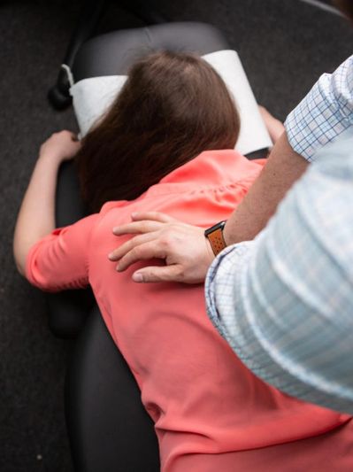 Chiropractor adjusting woman's back on treatment table.