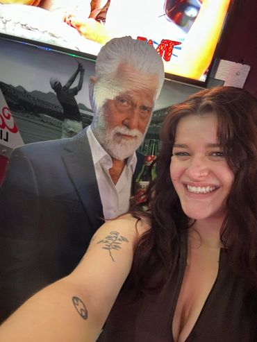 Woman smiling and taking a selfie with a life-sized cardboard cutout of a man.