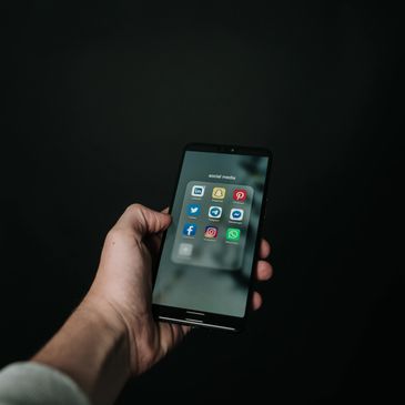 person holding a phone open to the home screen with applications visible 