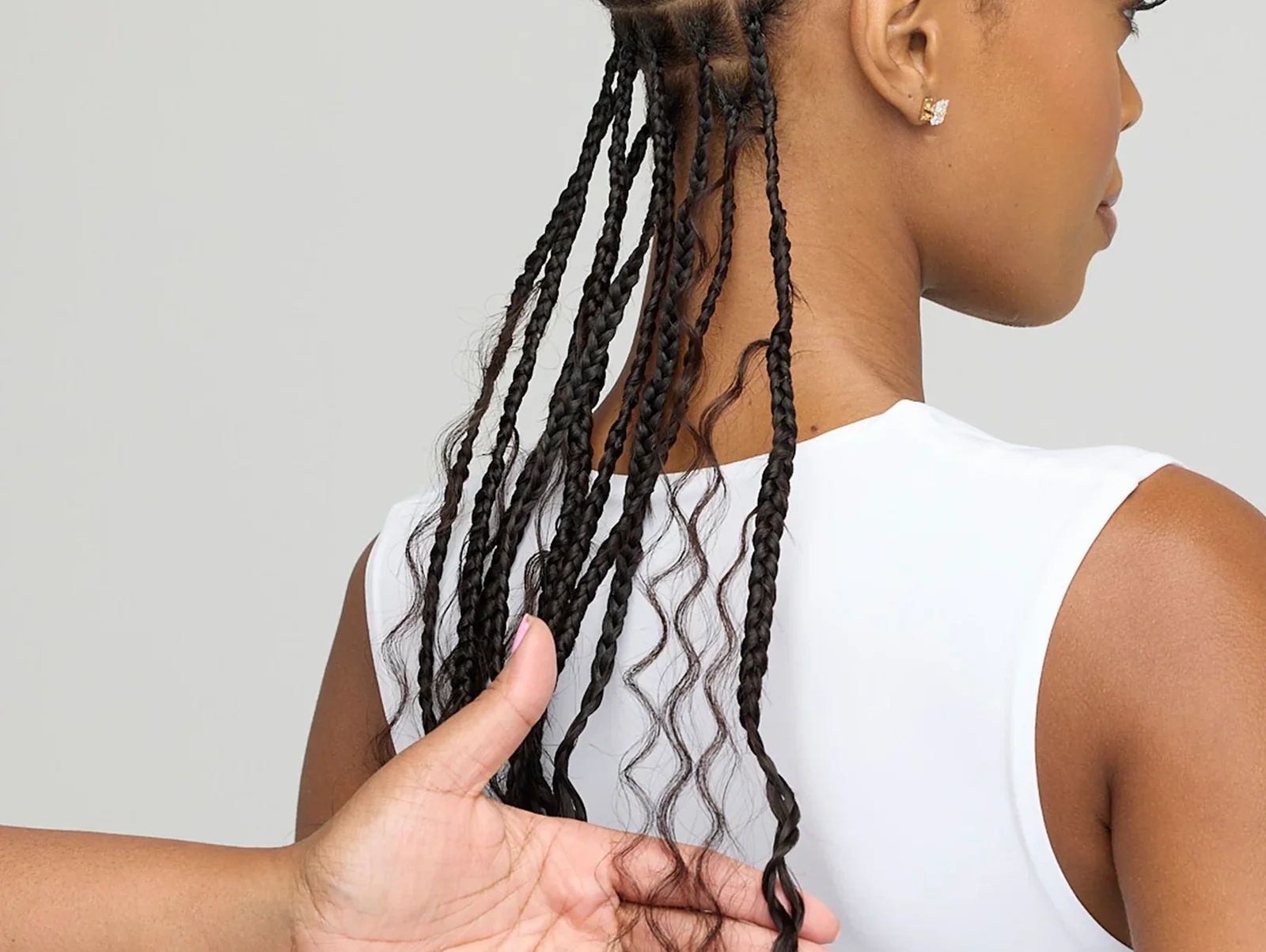 Person with braided hair being gently held by another hand.