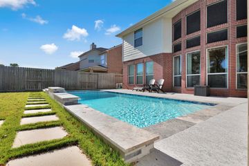 Modern backyard with a rectangular pool and seating area.