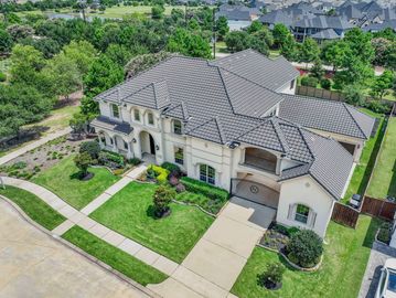 A large, elegant suburban house with a well-kept lawn and driveway.