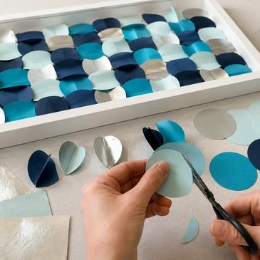 Manos cortando círculos de papel para un arte decorativo.