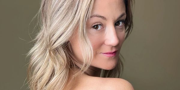 Blonde woman with bare shoulder looking back.