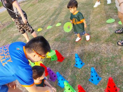 Children and adults engaged in an outdoor activity with colorful cones on grass.