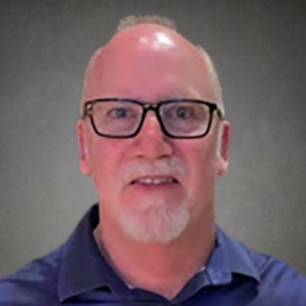 Portrait of a middle-aged man with glasses and a beard, wearing a blue shirt.