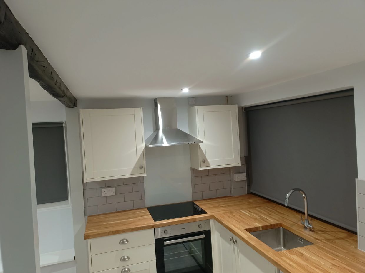 Modern kitchen with wooden countertops and white cabinets.