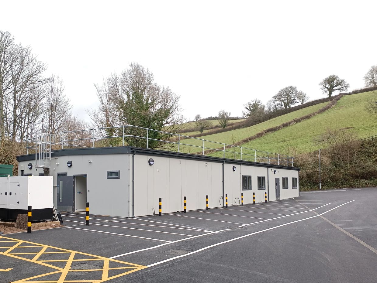 Modern modular building with adjacent parking lot in a rural setting.