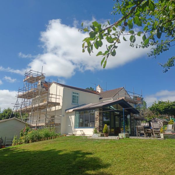 House undergoing exterior renovation with scaffolding on a sunny day.