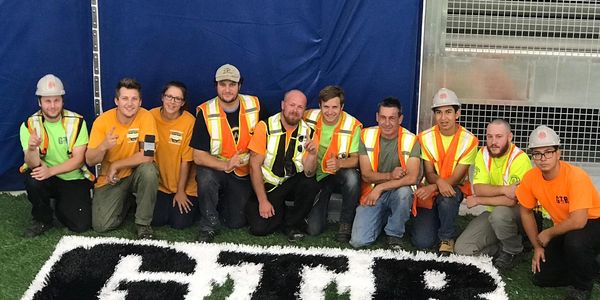 GTR TURF TEAM POSING PROUDLY ON TOP OF THE LOGO, AFTER COMPLETING A FIELD INSTALLATION