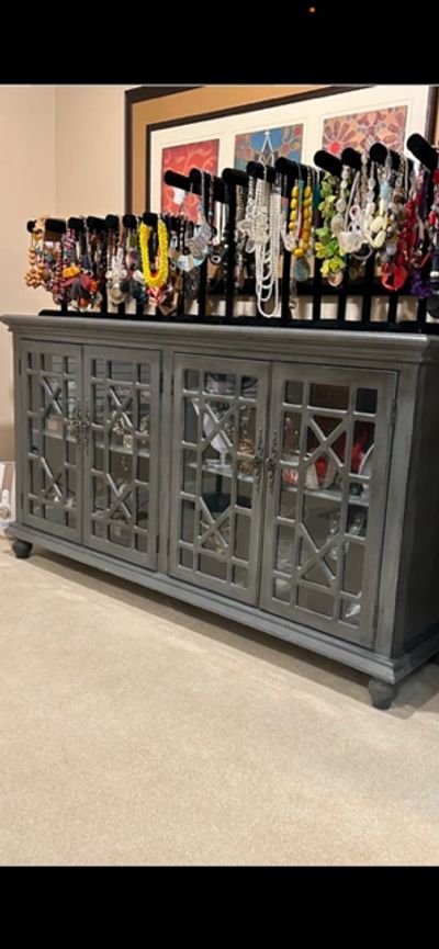 Grey cabinet with mirrored doors and jewelry on display above.