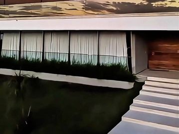 Casa moderna com fachada de vidro e escada branca.