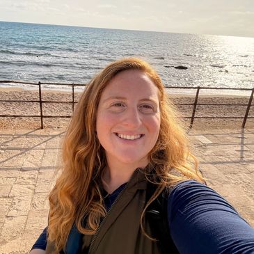 Smiling woman taking a selfie by the seaside on a sunny day.