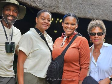 Group of four smiling people posing outdoors.