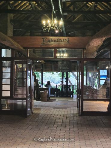 Entrance of a rustic lodge with chandelier and open doors.