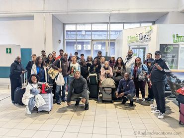 Group of travelers posing with luggage indoors.