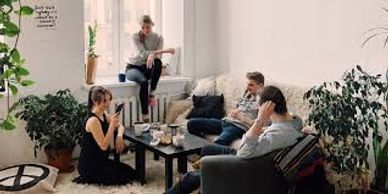 Four people enjoying coffee in a cozy living room with plants.