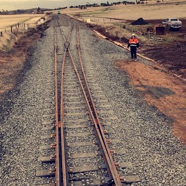 Rural railway tracks with a worker in the distance.