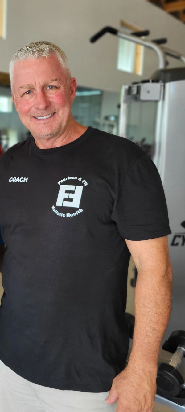 Smiling coach in a gym wearing a black Fearless &amp; Fit t-shirt.