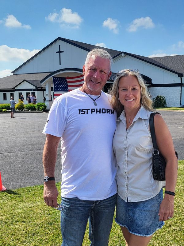 Couple smiling outside a church with an American flag.