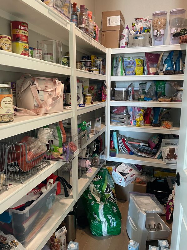 Overwhelmed walk-in pantry in Del Sur with food items jumbled together and cluttered floor