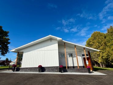 Modern white building with wooden pillars under a blue sky.