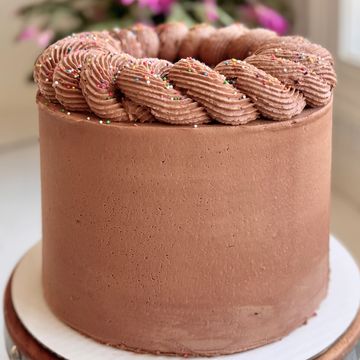 A smooth chocolate cake topped with swirled chocolate frosting and sprinkles.