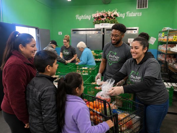 Volunteers distributing groceries to a family inside a community food pantry.