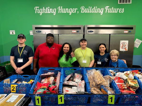 Group photo of volunteers with food baskets labeled for distribution.
