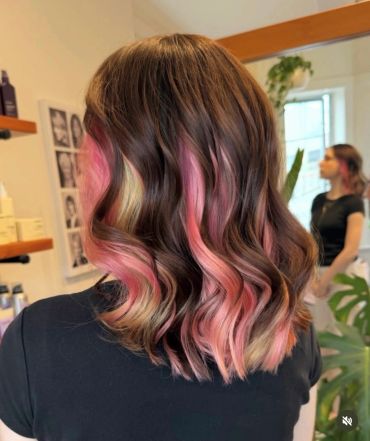 Wavy hair with pink highlights.