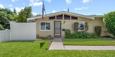 Single-story beige house with a well-kept lawn and an American flag.