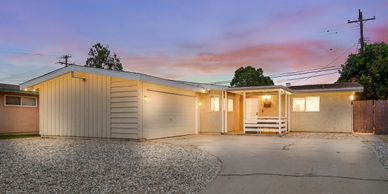 Single-story house with a garage at sunset and a gravel driveway.